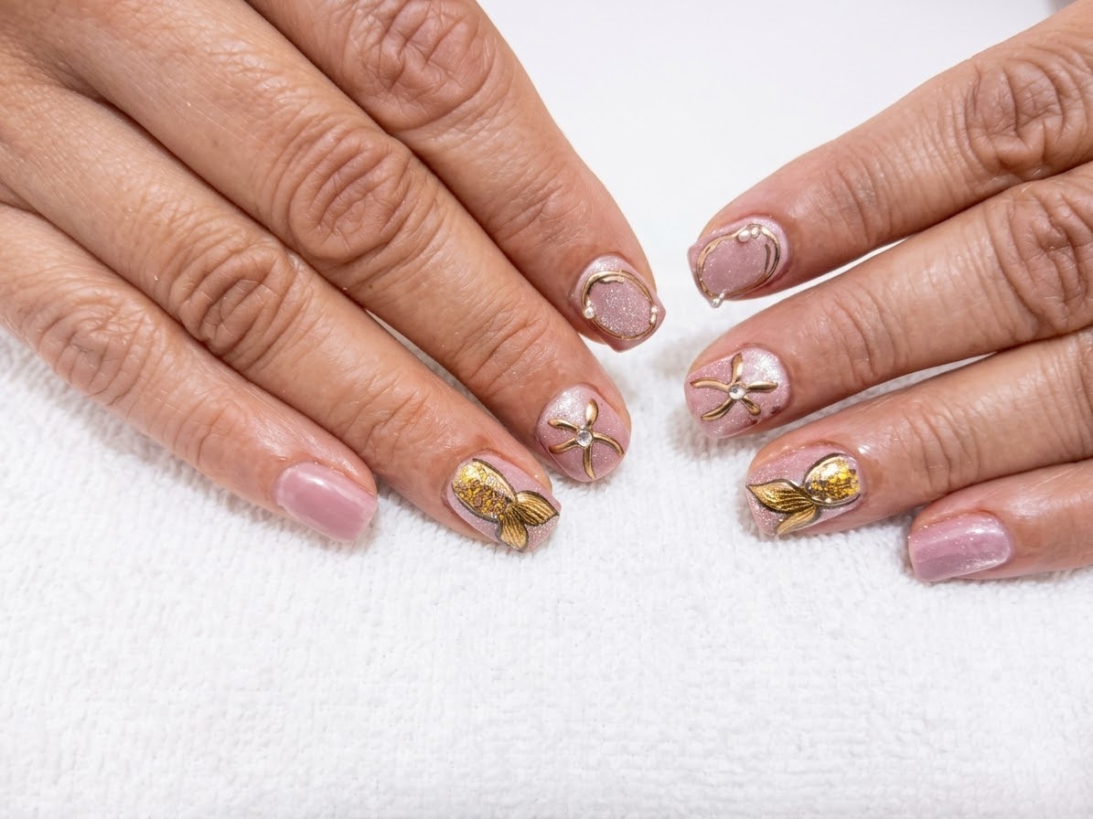 Diseño de uñas rosadas con mariposas y detalles dorados realizado en Glamourus